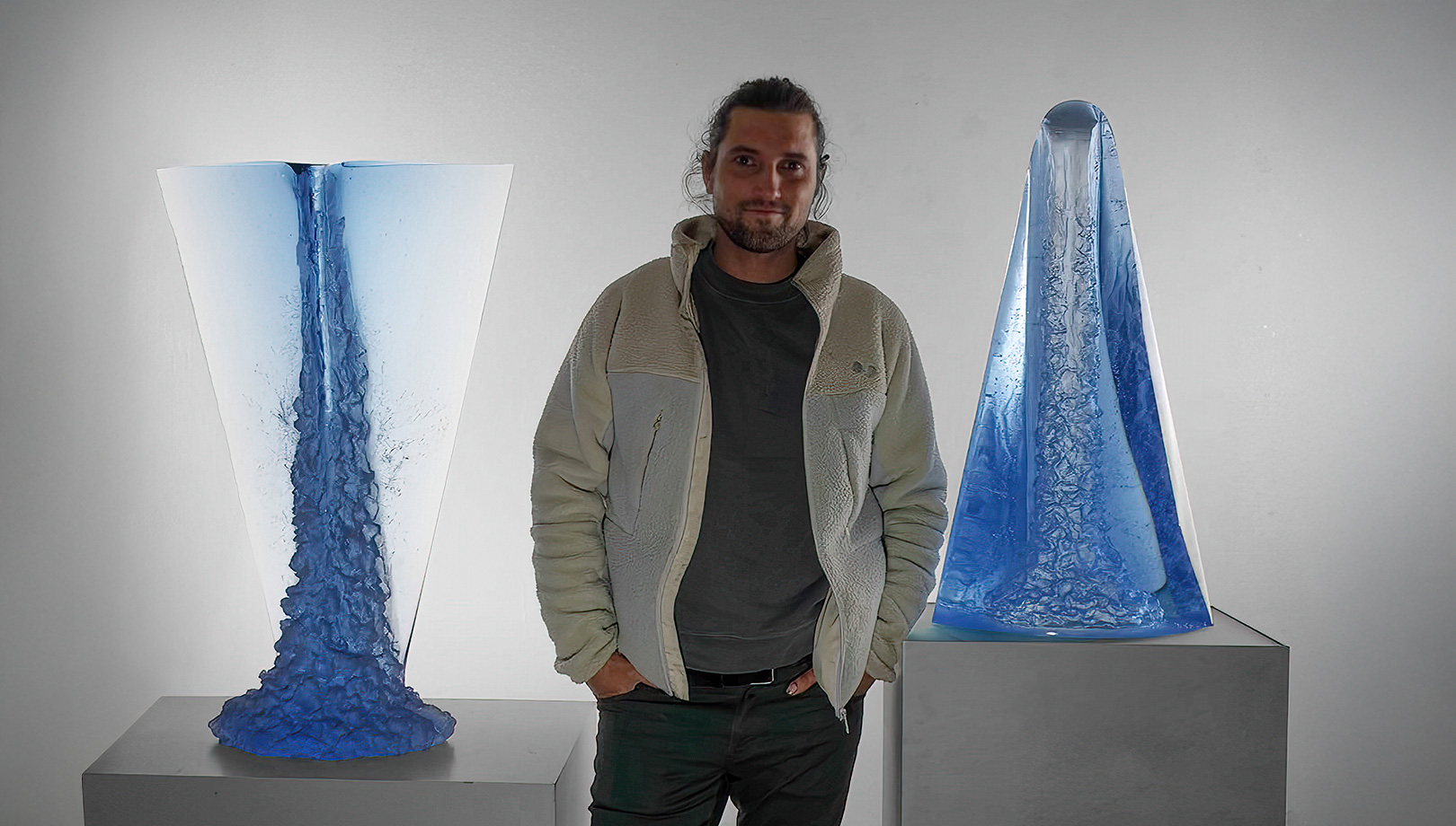 Artist Matyas Pavlik standing between his iconic glass sculptures Mystic Waterfall and Reverse Waterfall, showcasing modern glass artistry